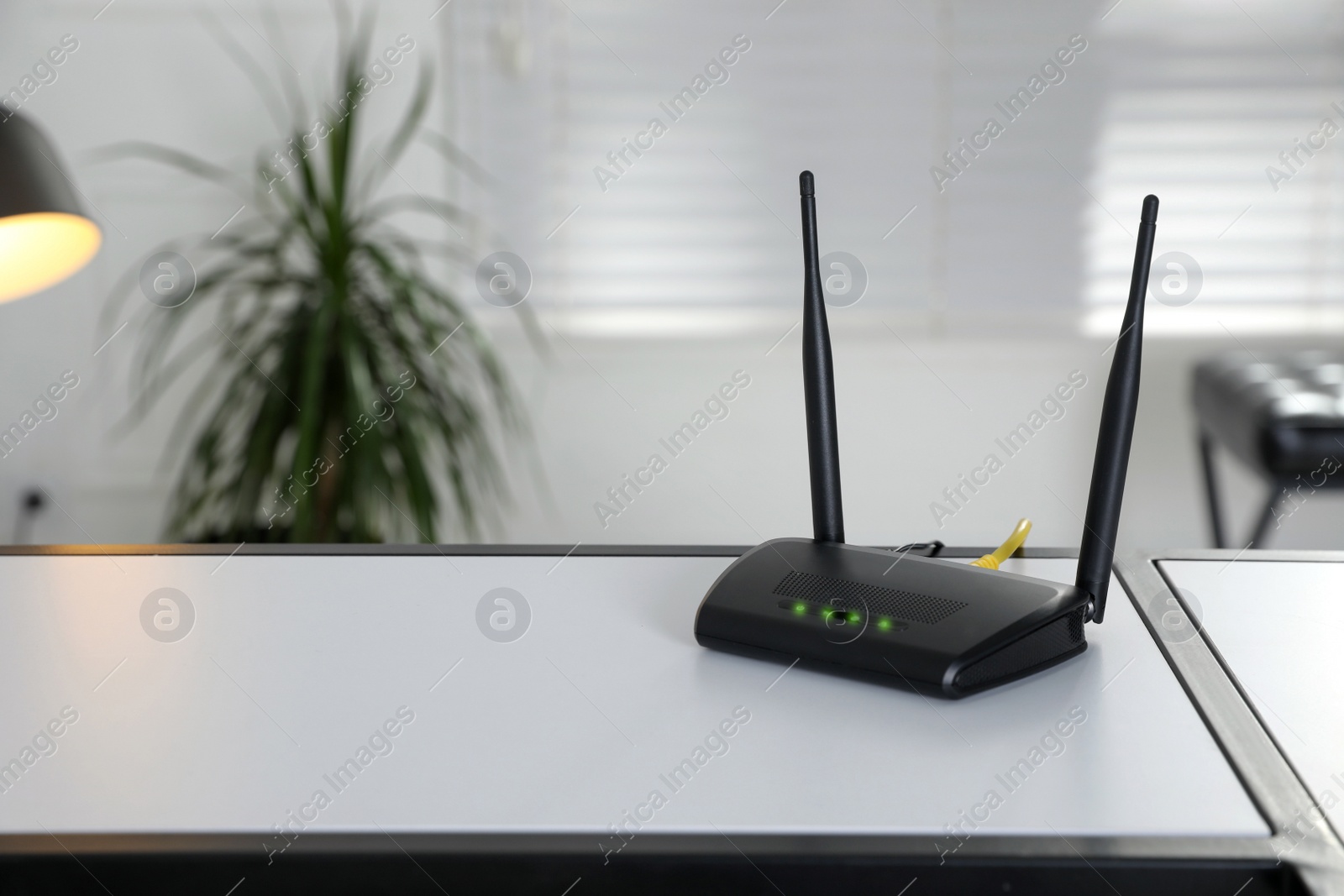 Photo of Modern Wi-Fi router on table indoors. Space for text