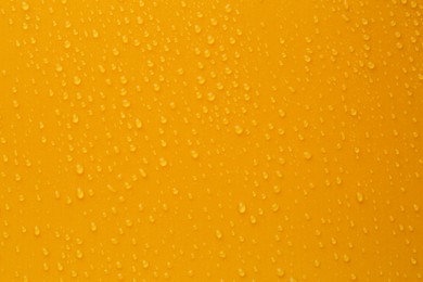 Water drops on orange background, top view