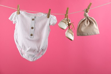 Photo of Baby clothes hanging on washing line against pink background