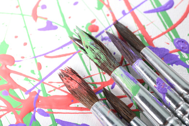 Photo of Brushes on canvas with colorful paint splashes, closeup. Art and creativity