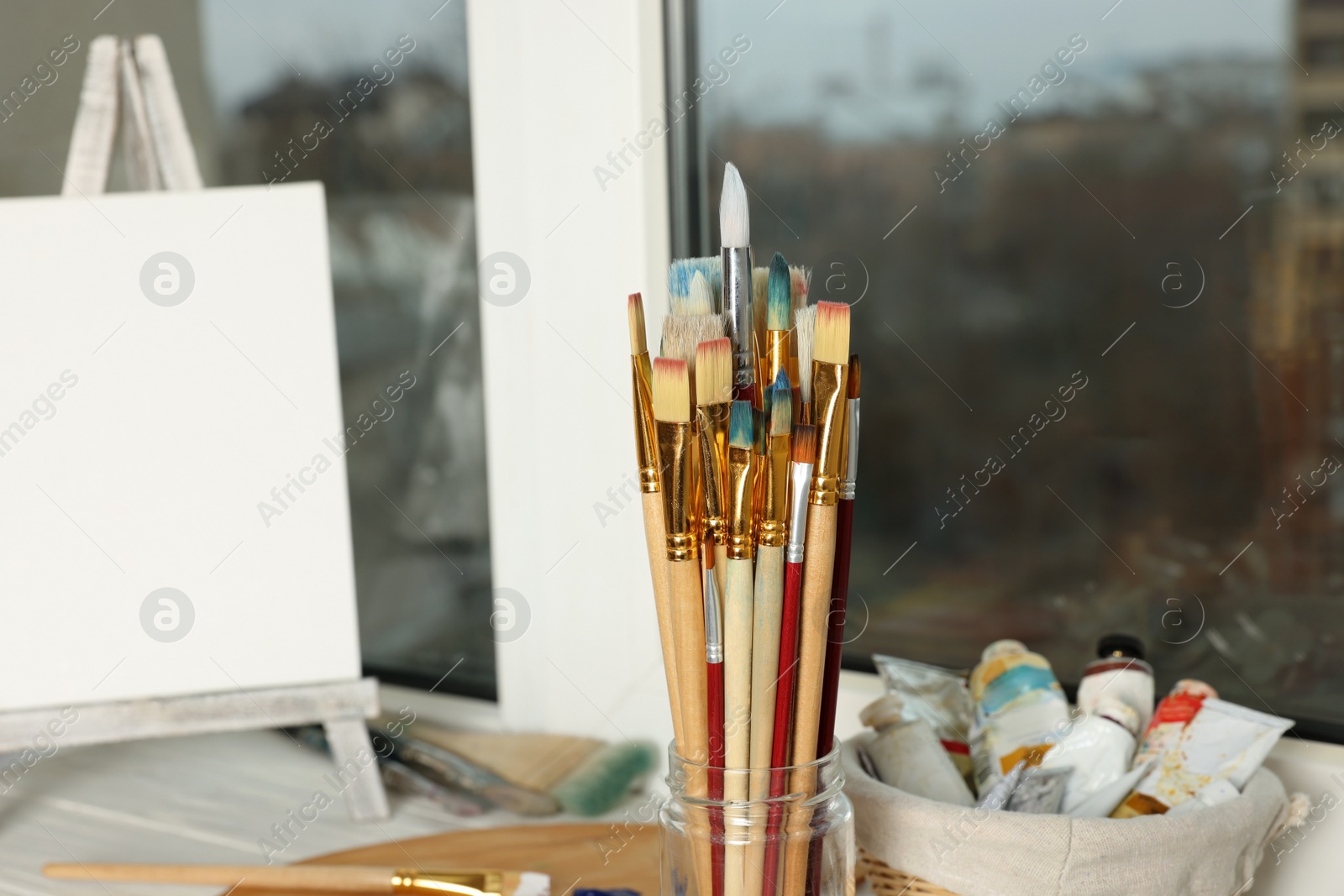 Photo of Glass jar with many paintbrushes near window