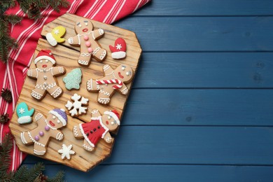 Delicious Christmas cookies and fir branches on blue wooden table, flat lay. Space for text