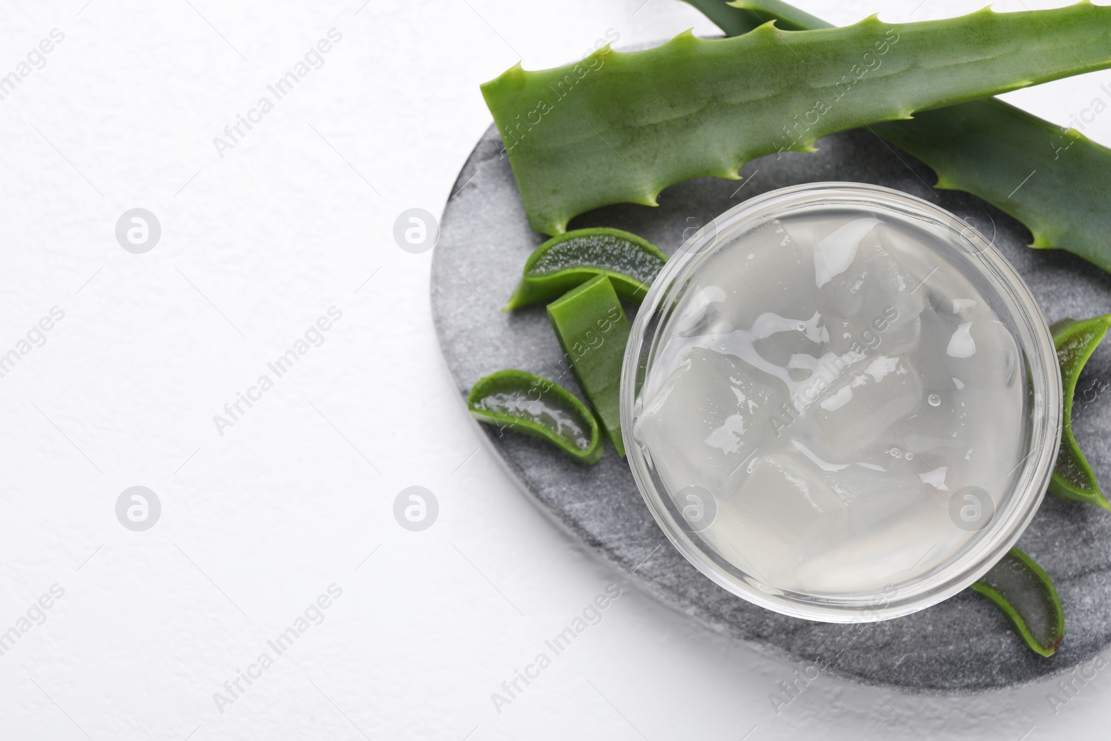 Photo of Aloe vera gel and slices of plant on white background, top view. Space for text