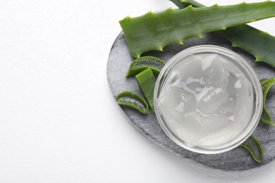 Aloe vera gel and slices of plant on white background, top view. Space for text