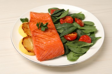 Photo of Tasty grilled salmon with basil, tomatoes and lemon on white wooden table, closeup