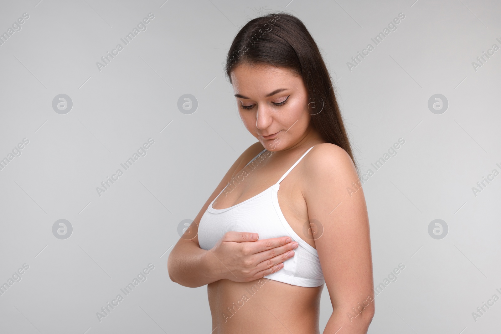 Photo of Mammology. Woman doing breast self-examination on light grey background