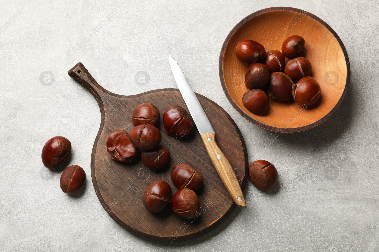 Photo of Fresh edible sweet chestnuts and knife on grey table, flat lay