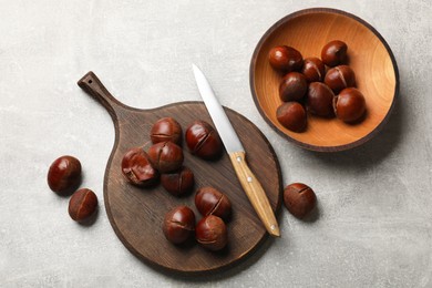 Photo of Fresh edible sweet chestnuts and knife on grey table, flat lay