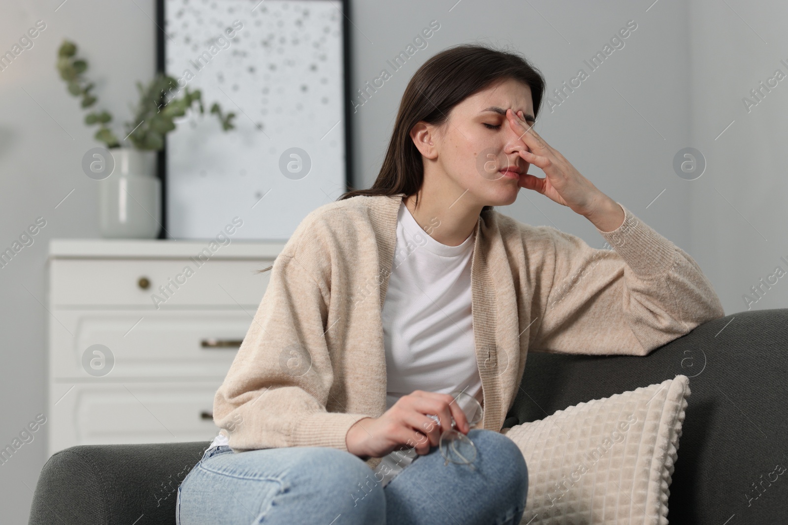 Photo of Overwhelmed woman with glasses sitting on sofa at home