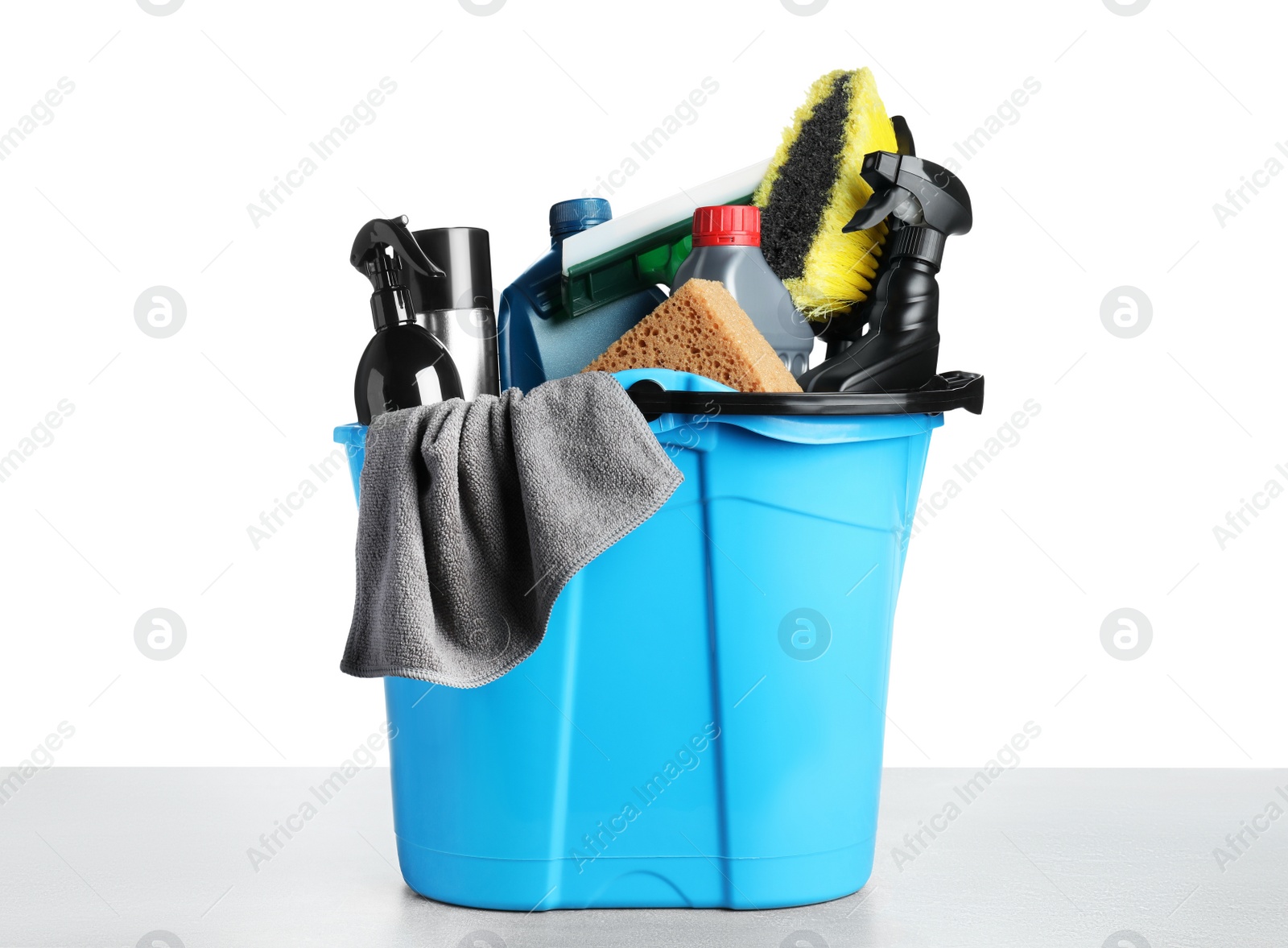 Photo of Bucket with many different car wash products on grey table against white background