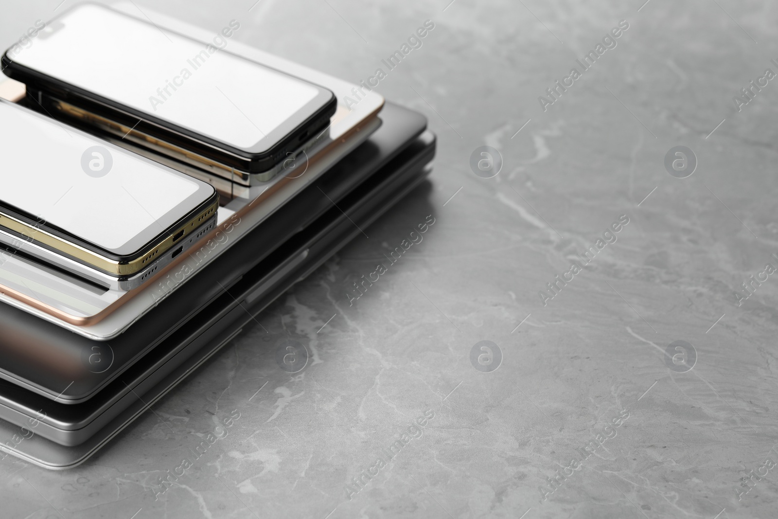 Photo of Stack of electronic devices on grey stone table, closeup. Space for text