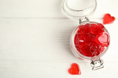 Photo of Sweet heart shaped jelly candies on white wooden table, flat lay. Space for text