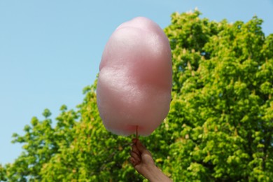 Woman holding sweet cotton candy outdoors, closeup