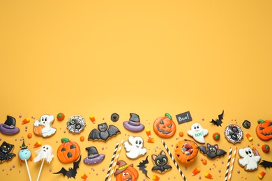 Photo of Flat lay composition with decorated gingerbread cookies on yellow background, space for text. Halloween celebration