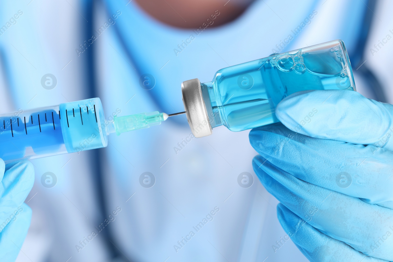 Photo of Doctor filling syringe with medication from glass vial, closeup