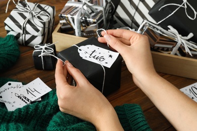 Woman decorating gift box at wooden table, closeup. Creating advent calendar