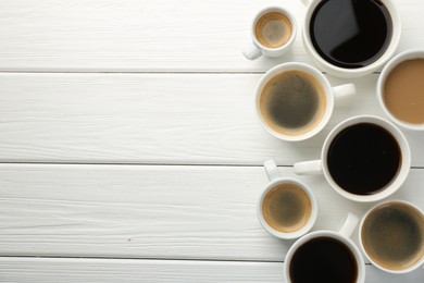 Photo of Different coffee drinks in cups on white wooden table, flat lay. Space for text