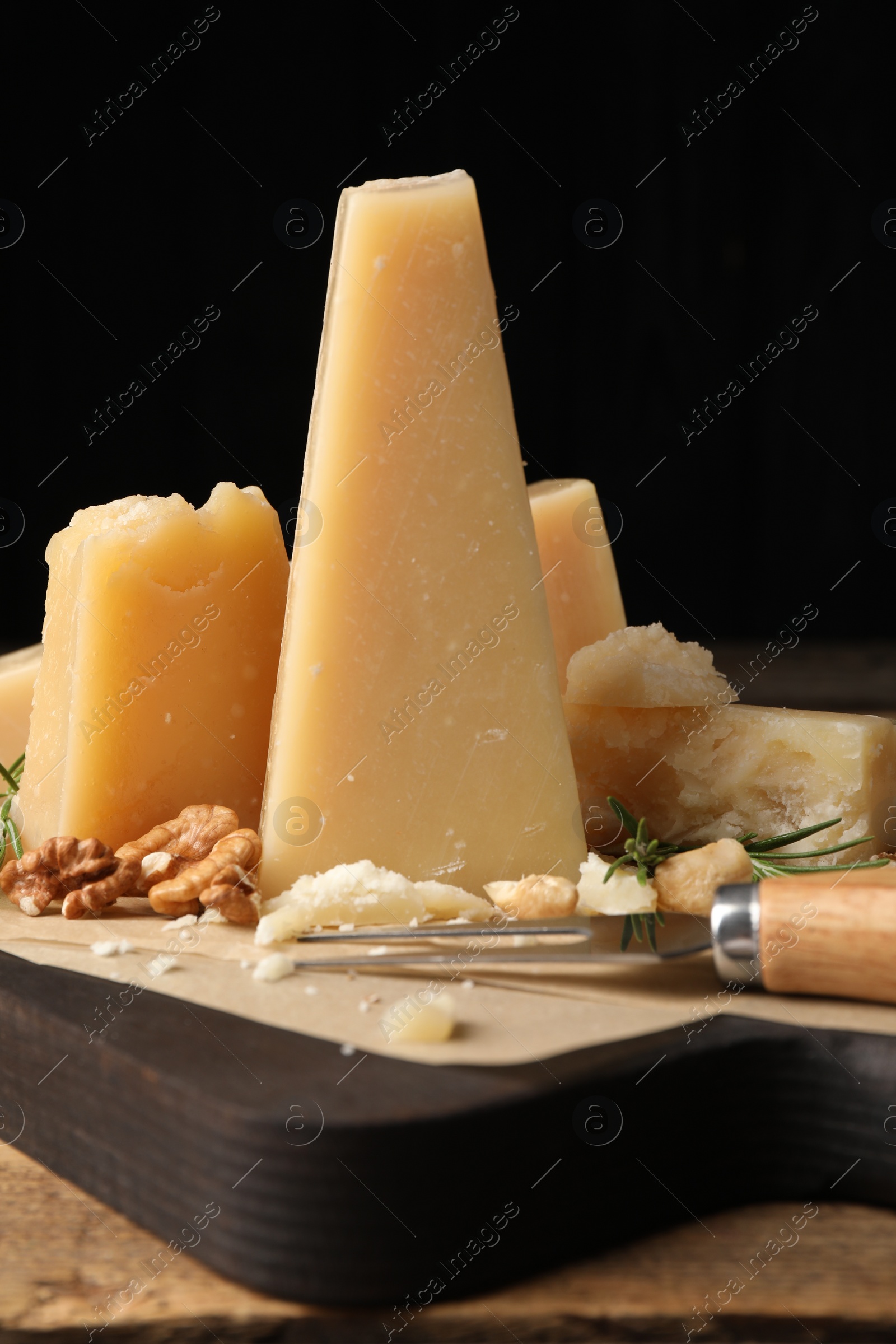 Photo of Delicious parmesan cheese with walnuts and rosemary on wooden table, closeup