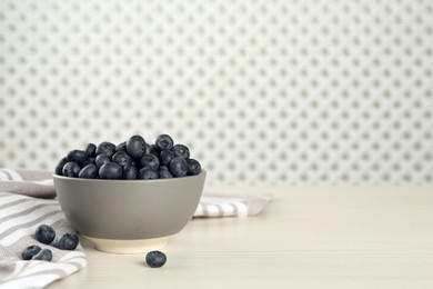 Photo of Ceramic bowl with blueberries on white wooden table, space for text. Cooking utensil