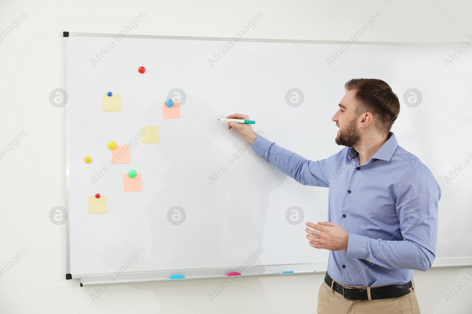 Photo of Portrait of young teacher writing on whiteboard in classroom