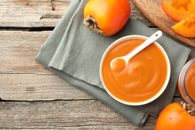 Photo of Delicious persimmon jam and fresh fruits on wooden table, flat lay. Space for text