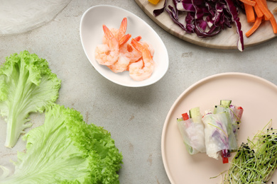 Photo of Flat lay composition with delicious rolls wrapped in rice paper on light grey table