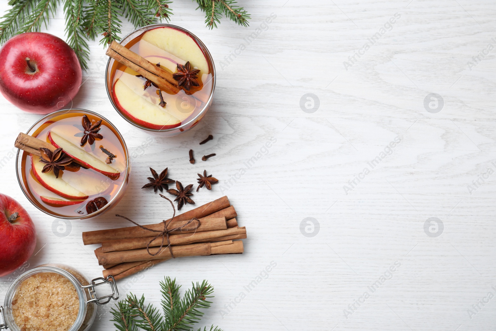 Photo of Hot mulled cider, ingredients and fir branches on white wooden table, flat lay. Space for text