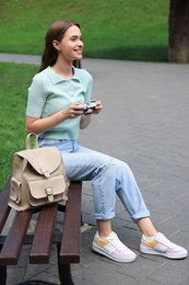 Photo of Young woman with camera on bench in park. Interesting hobby