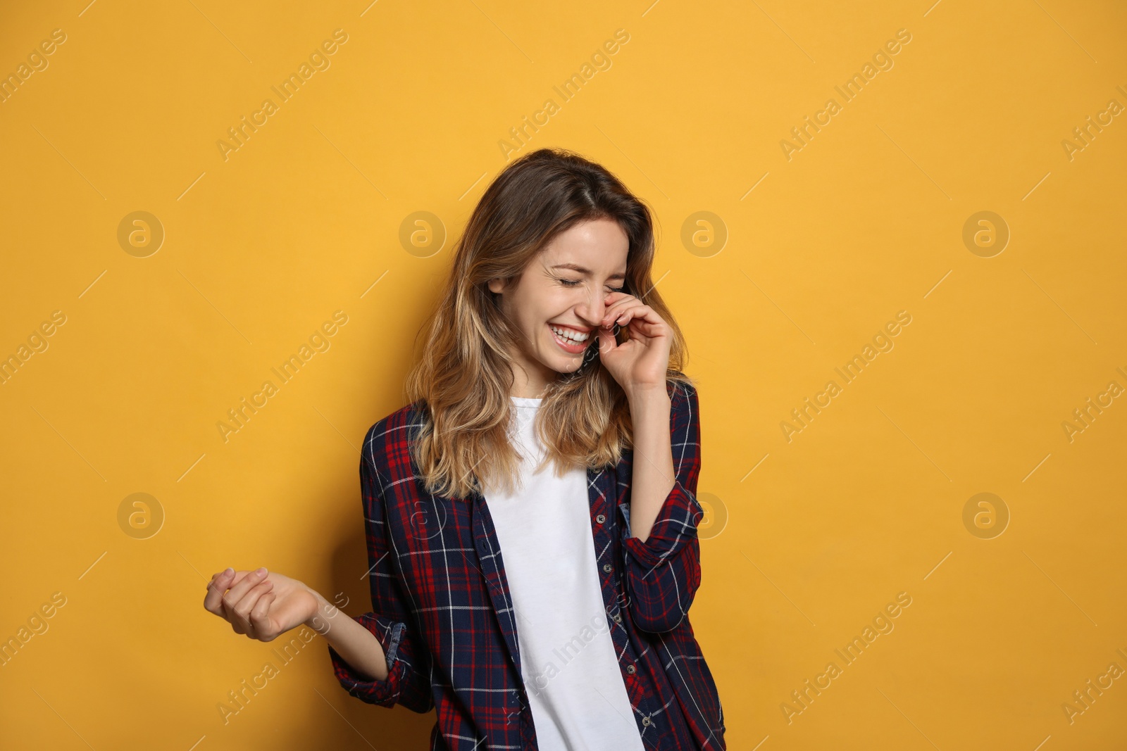 Photo of Cheerful young woman laughing on yellow background