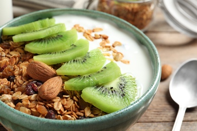 Image of Tasty granola with yogurt and sliced kiwi for breakfast on table, closeup