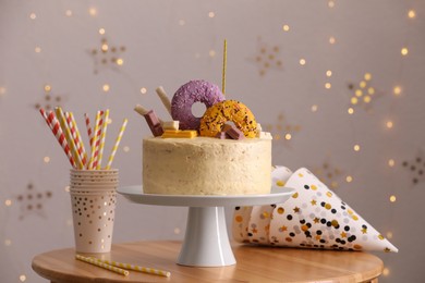 Photo of Delicious cake decorated with sweets and festive items on wooden table