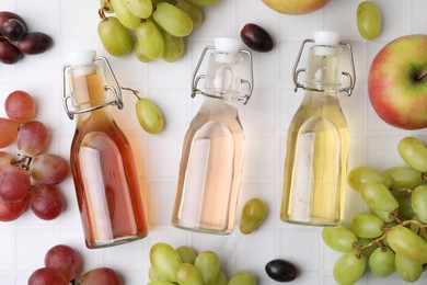 Photo of Different types of vinegar and ingredients on light tiled table, flat lay