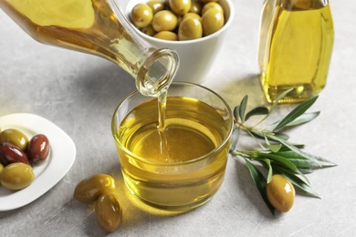 Photo of Pouring fresh olive oil into glass on table