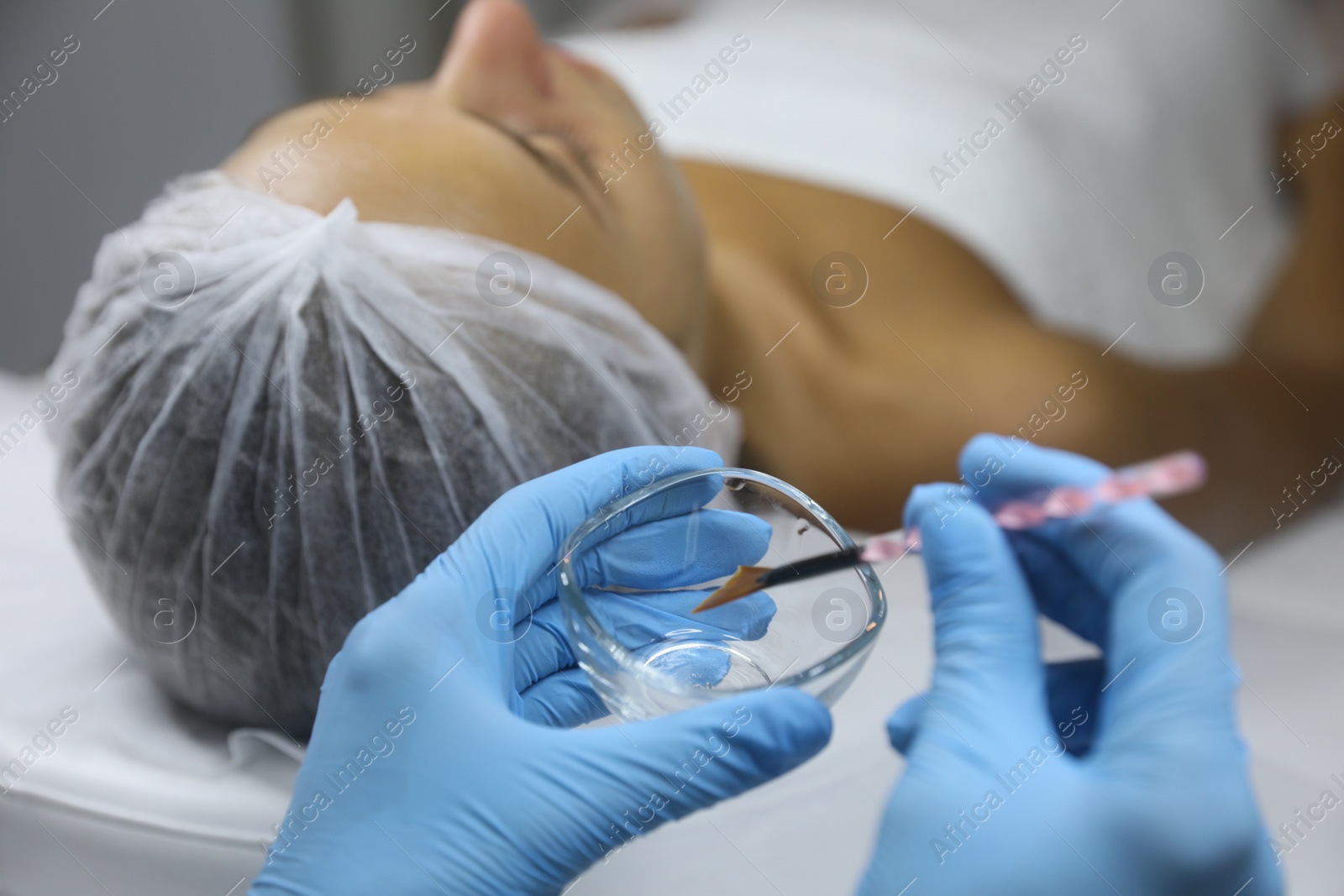 Photo of Cosmetologist with bowl and brush in salon. Peeling procedure
