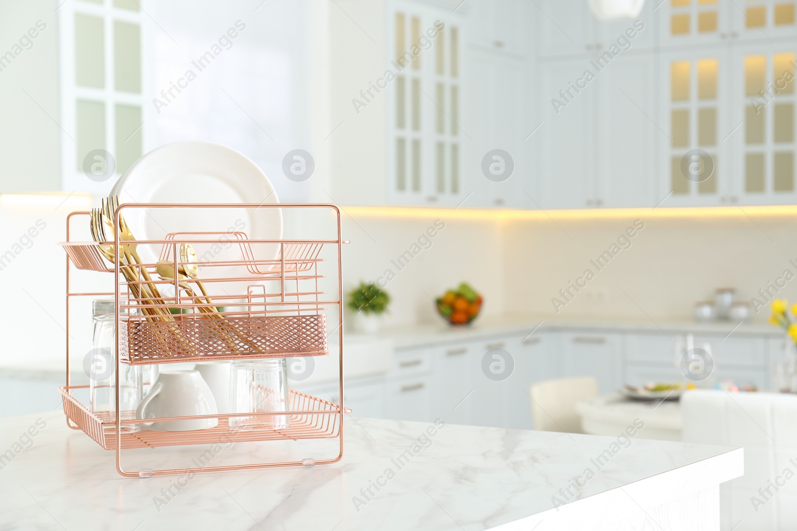 Photo of Clean dishes on drying rack in modern kitchen interior, space for text