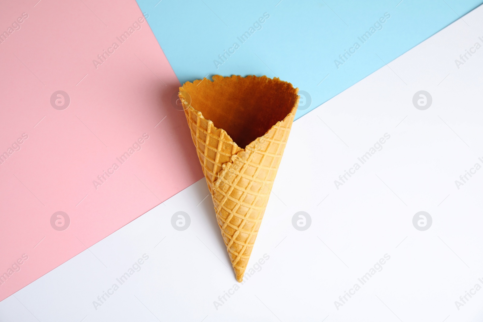 Photo of Empty wafer ice cream cone on color background, top view