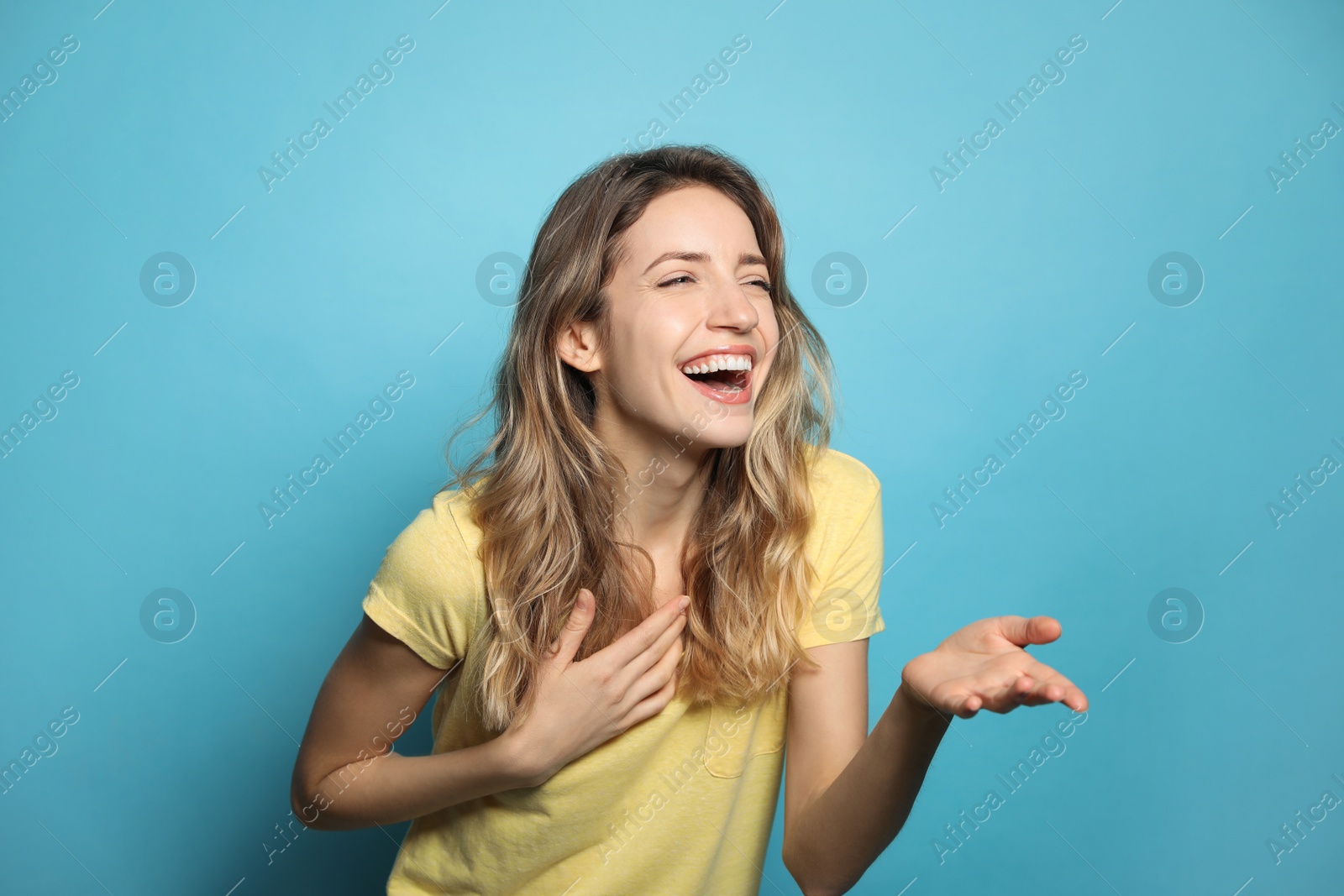 Photo of Cheerful young woman laughing on light blue background