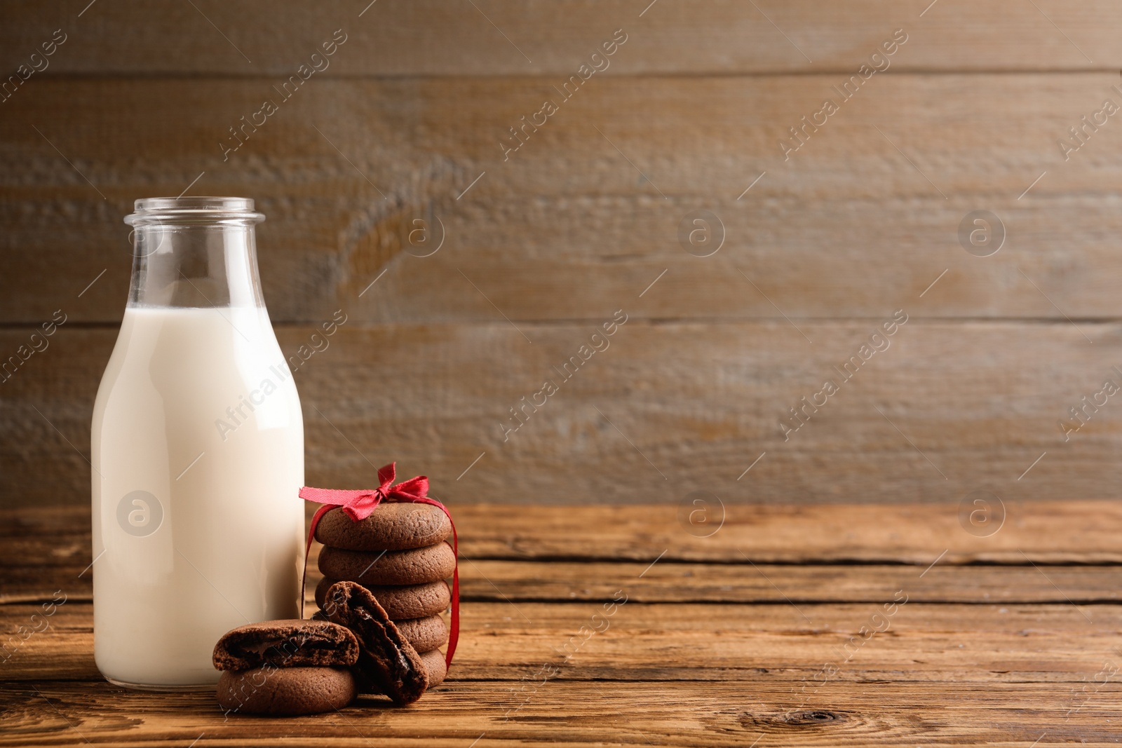 Photo of Tasty chocolate cookies and milk on wooden table. Space for text