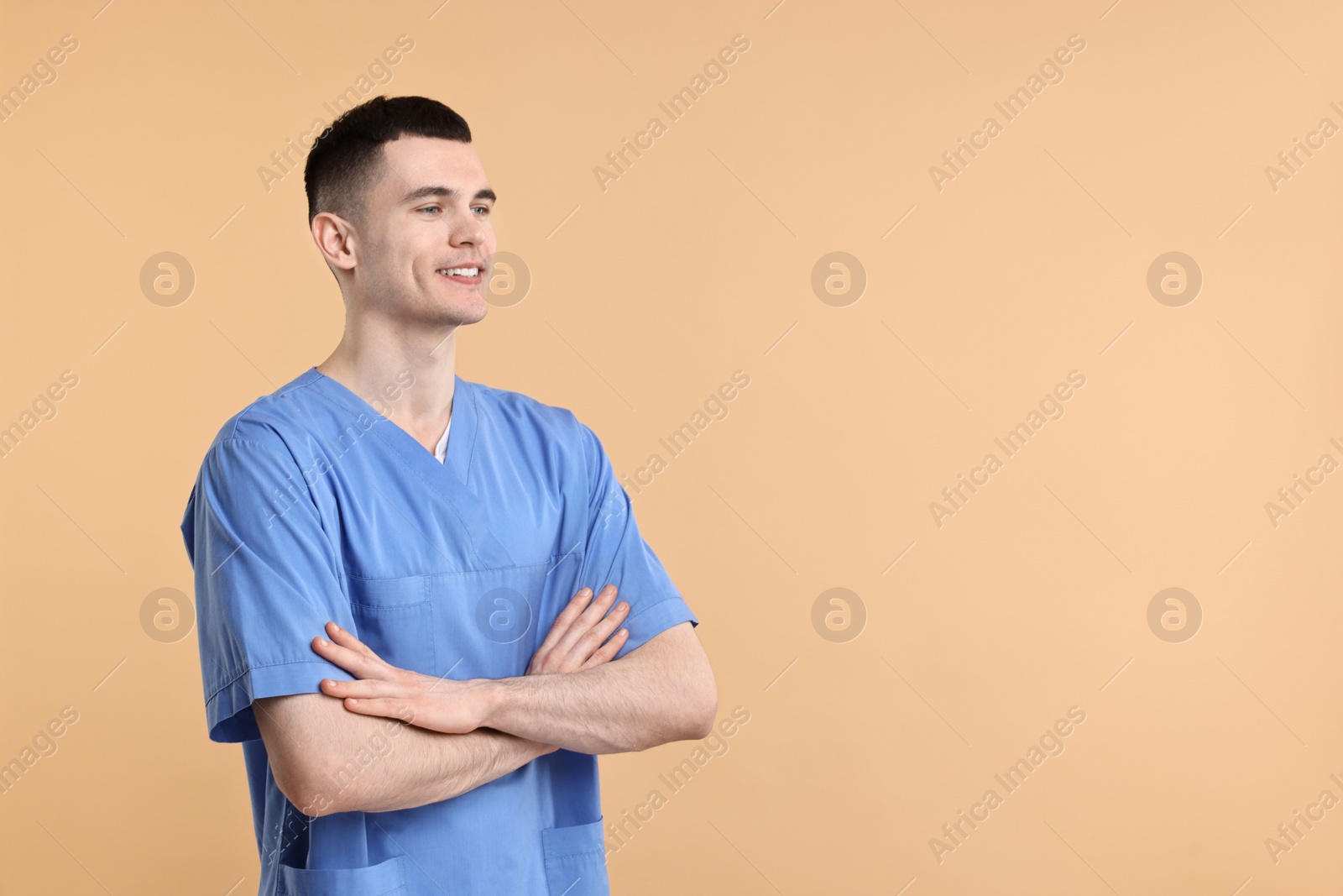 Photo of Portrait of smiling medical assistant with crossed arms on beige background. Space for text