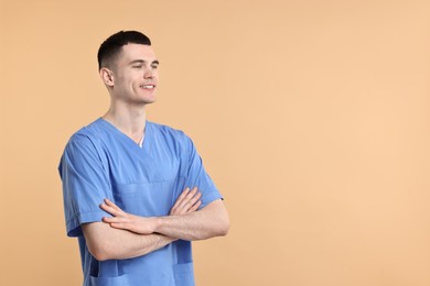 Portrait of smiling medical assistant with crossed arms on beige background. Space for text