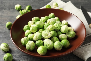 Photo of Plate of fresh Brussels sprouts and napkin on grey table