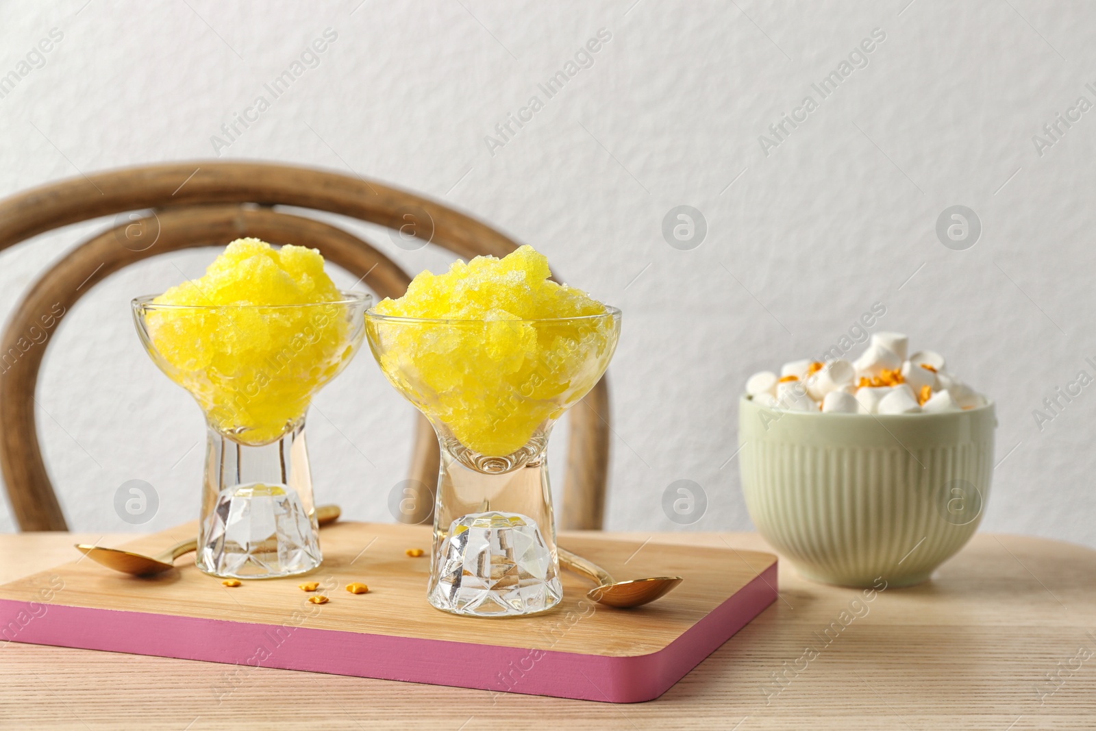 Photo of Bowls with snow ice cream dessert and marshmallows on table against light wall. Space for text