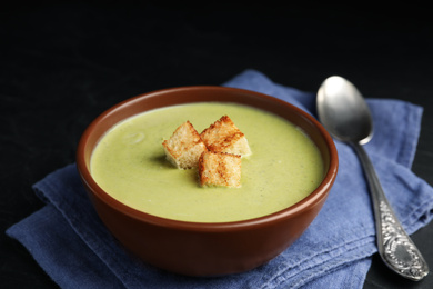 Photo of Delicious broccoli cream soup served on black table