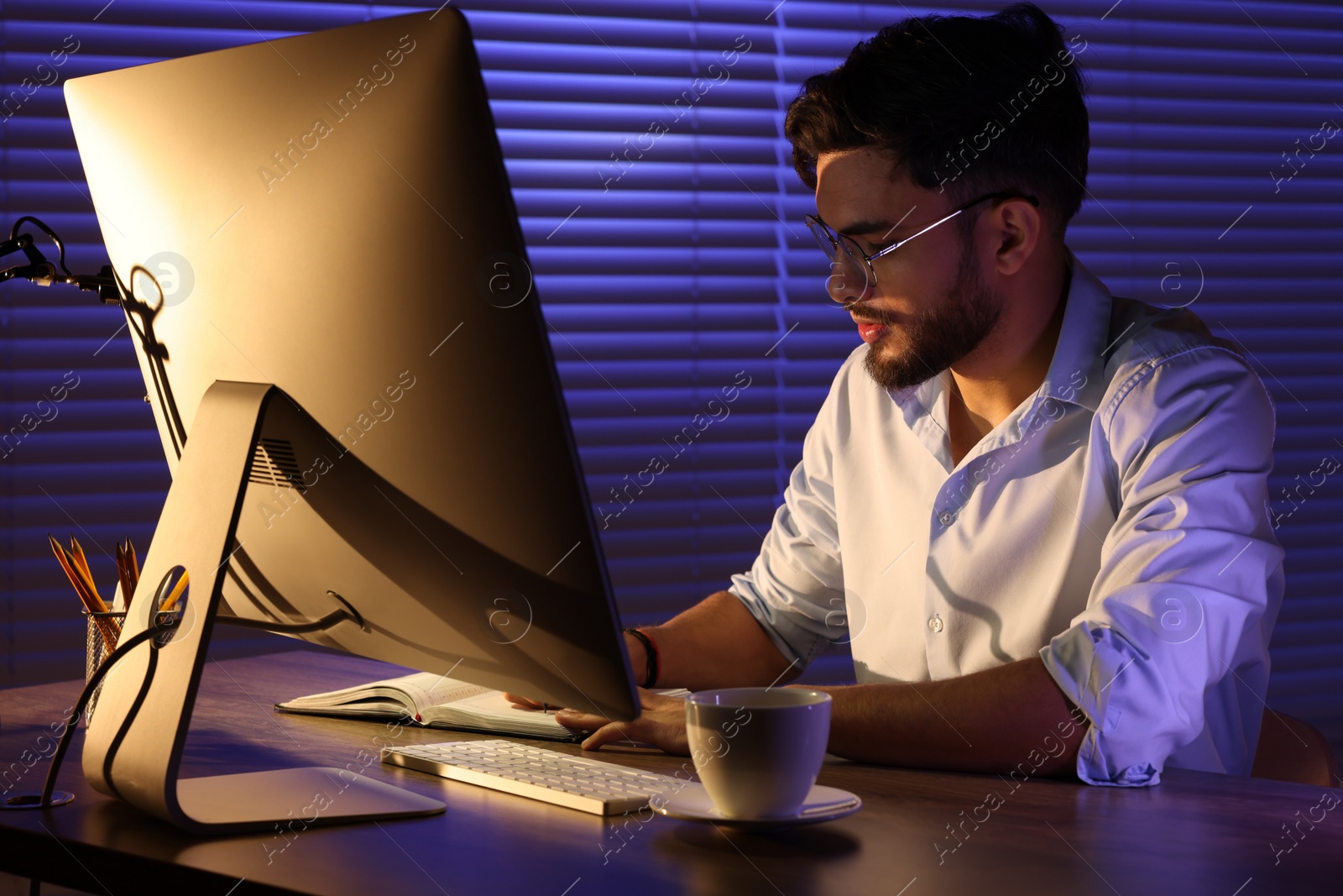 Photo of Tired young man working late in office