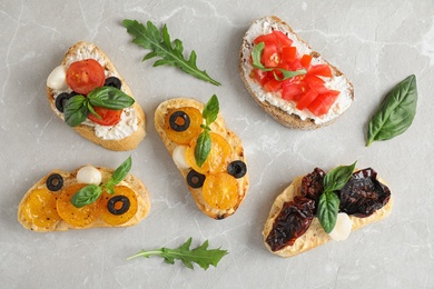 Photo of Delicious tomato bruschettas on light grey marble background, flat lay