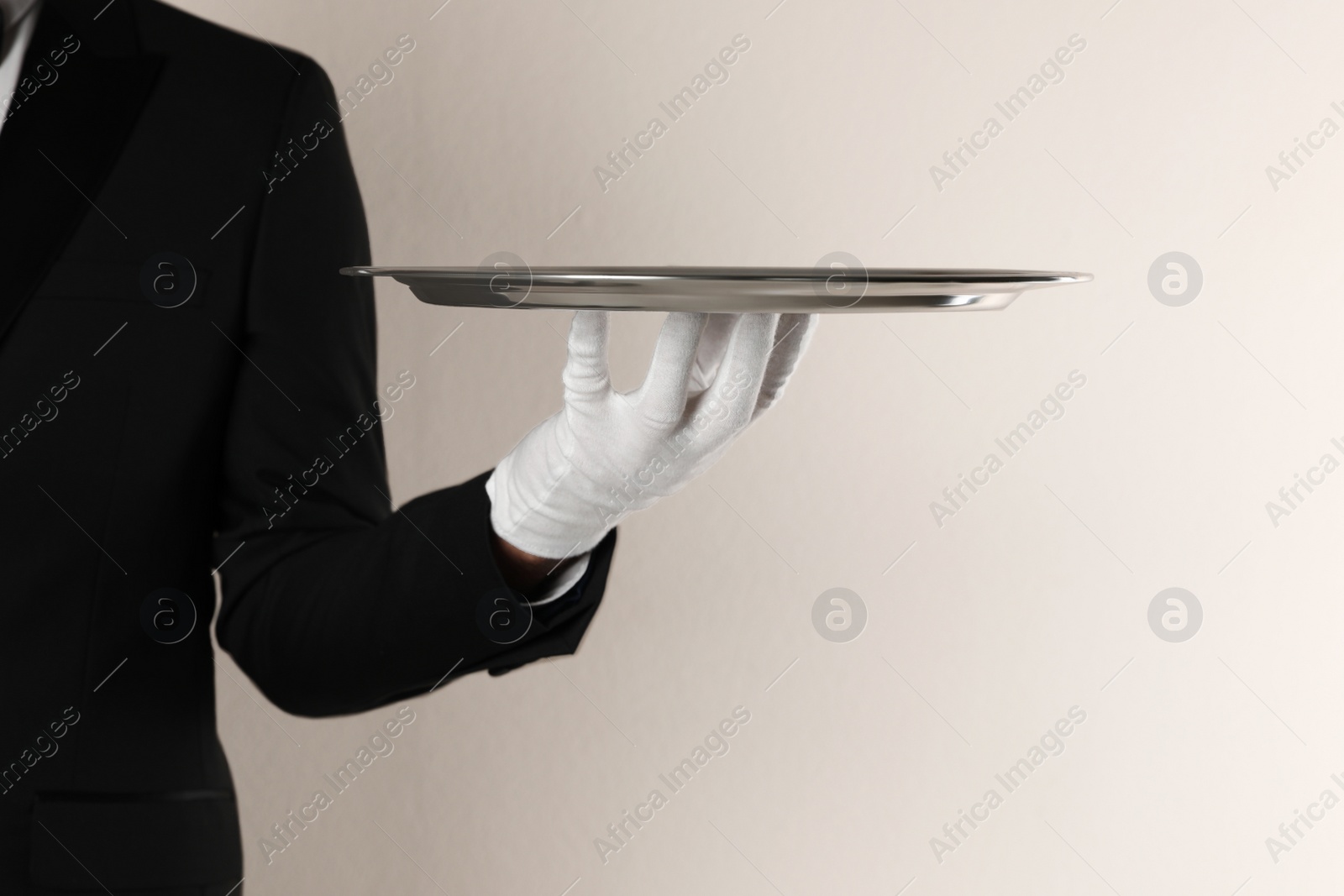 Photo of Butler with tray on beige background, closeup