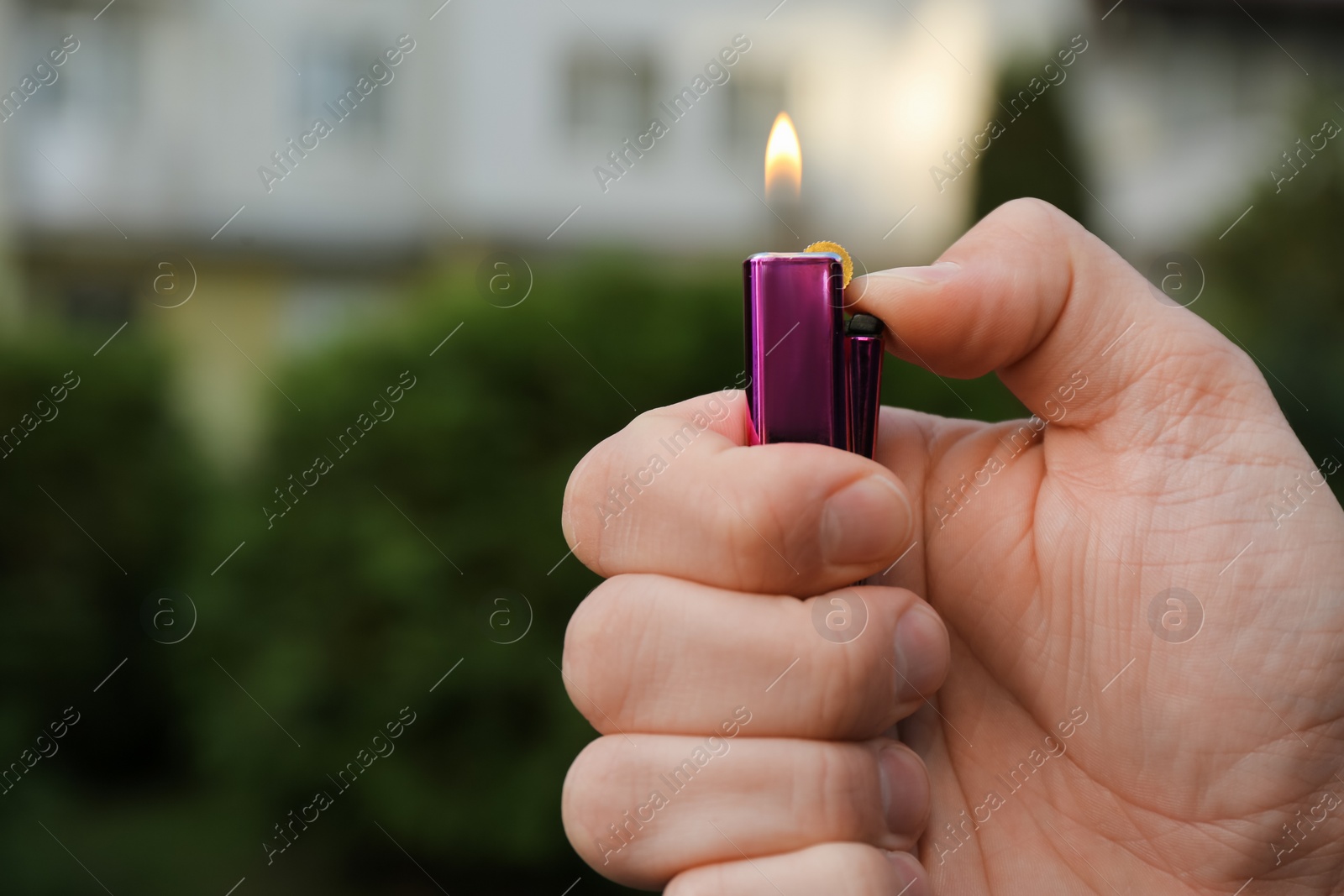 Photo of Man holding lighter with burning flame outdoors, closeup. Space for text