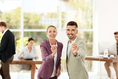 Photo of Happy young employees with darts in office