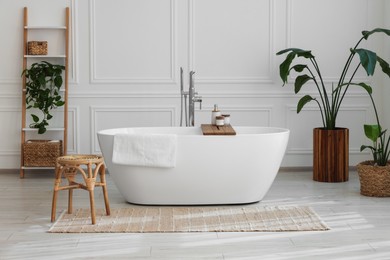 Photo of Stylish bathroom interior with beautiful tub, stool and houseplants