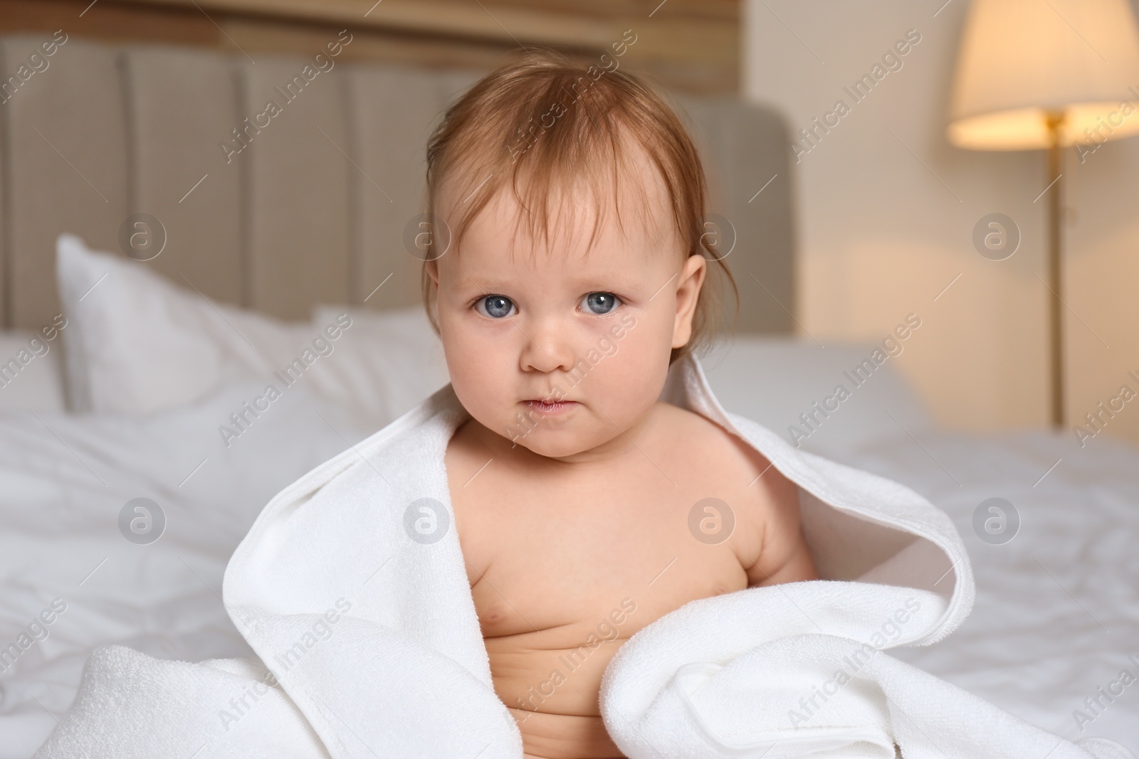 Photo of Cute little baby with soft towel on bed after bath